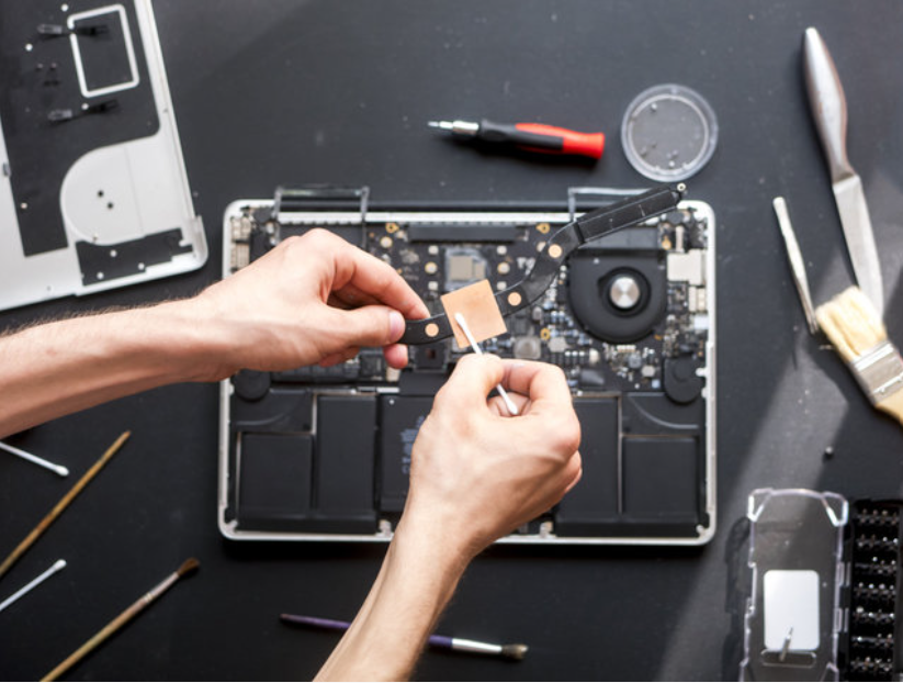 unassembled laptop with a person replacing an internal component